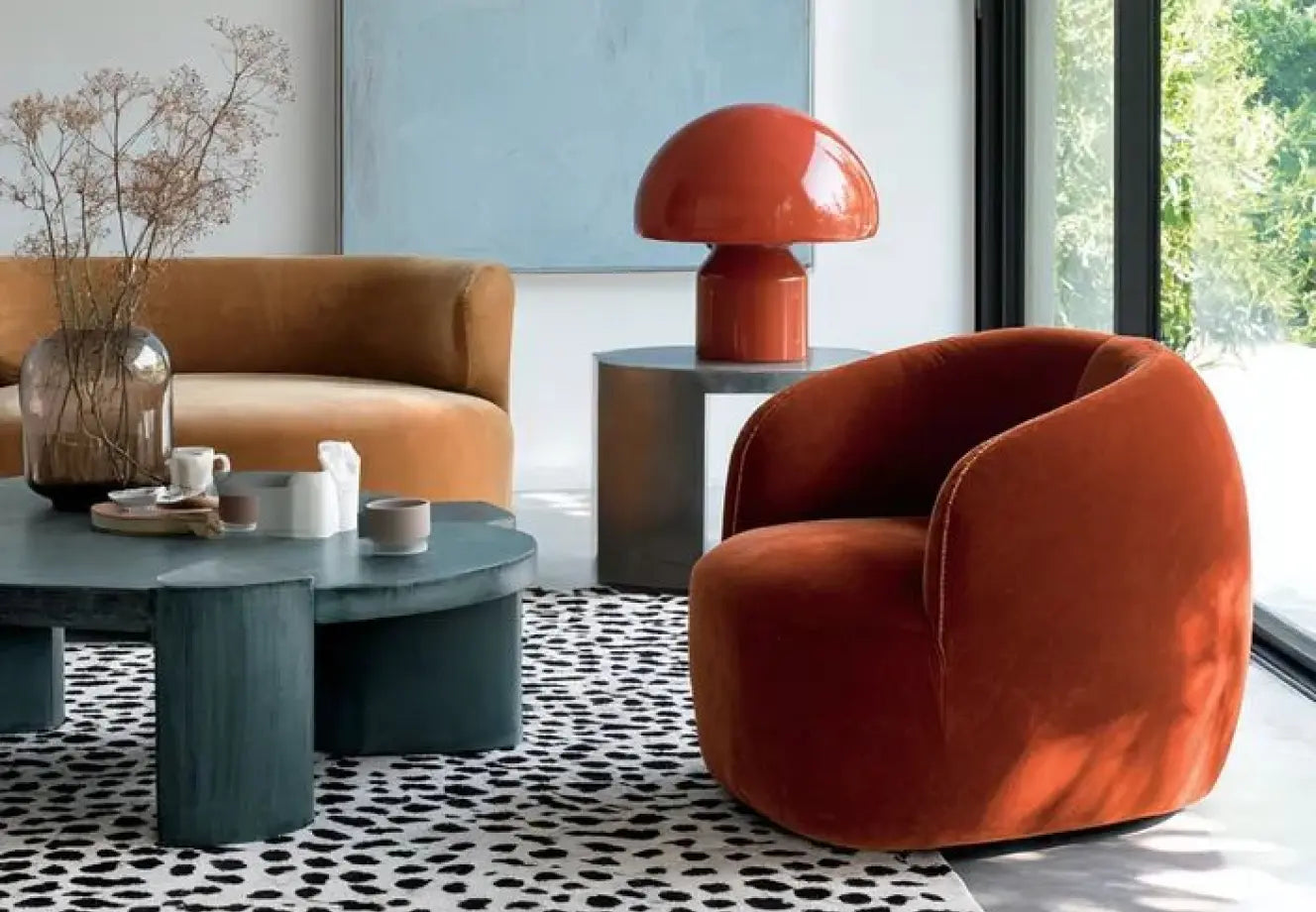 Bold color home decor with rust velvet chair, sculptural table lamp, and modern living room styling