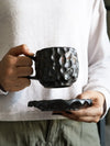 Textured Japanese ceramic coffee cup held in hand, showcasing artisan design and grip comfort