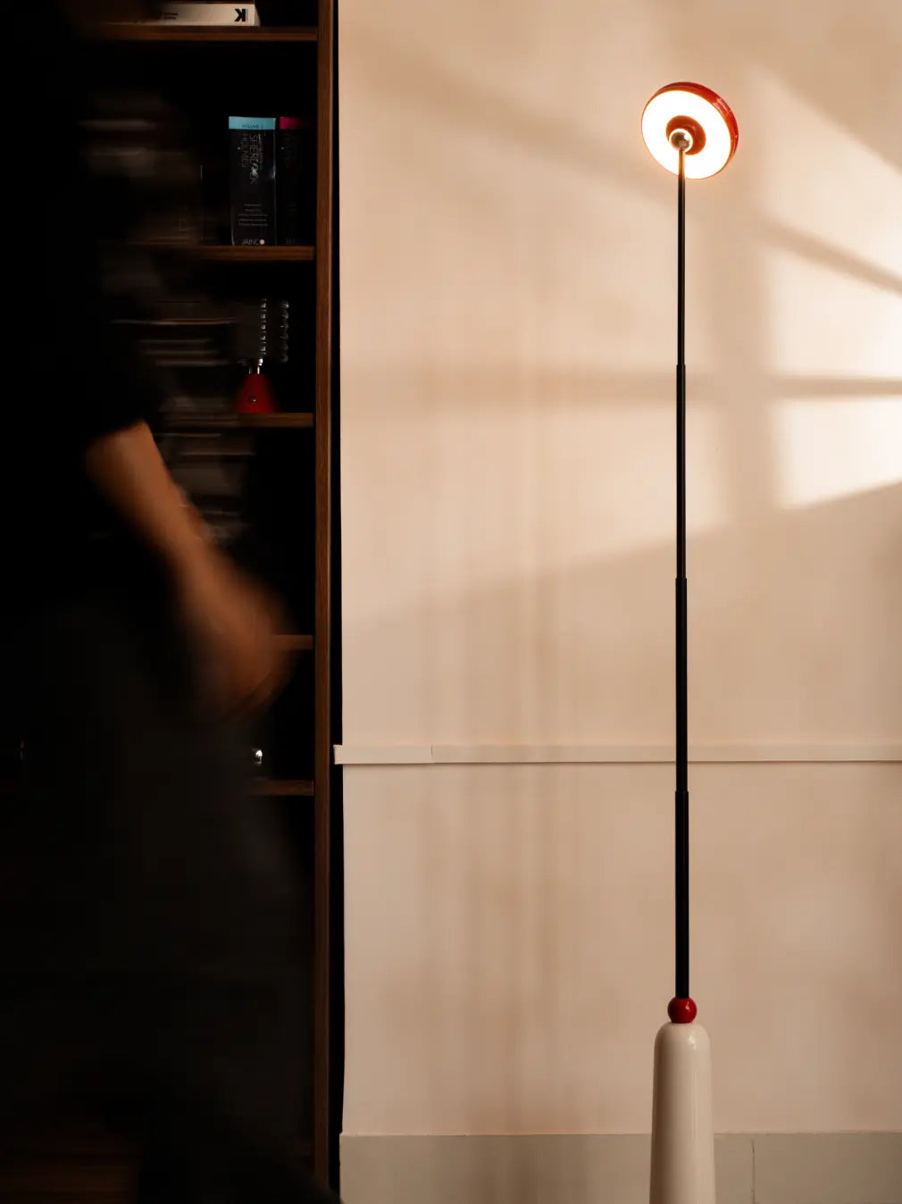 3-in-1 Frisbee Retractable Lamp used as tall floor lamp casting warm light on wall, modern living room.