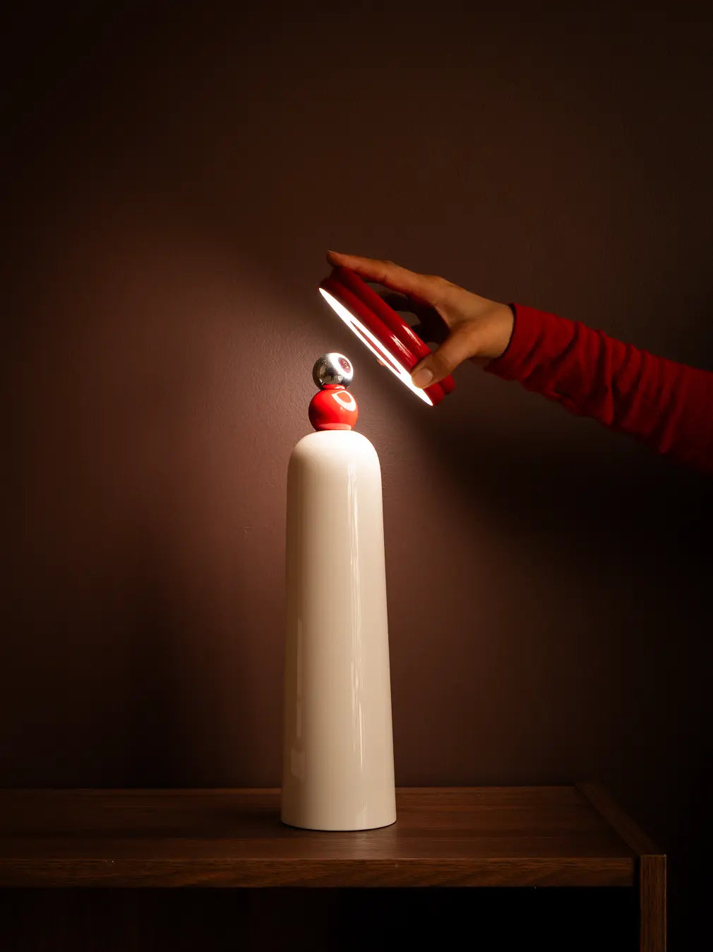 Hand placing magnetic Frisbee lampshade on 3-in-1 retractable table lamp with warm LED light.