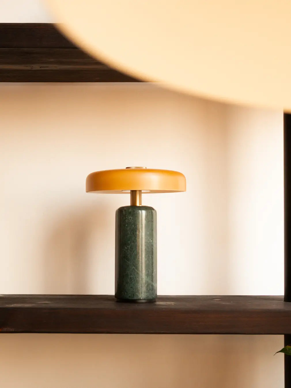 Alba Moss Marble Table Lamp displayed on a wooden shelf with green marble and amber glass