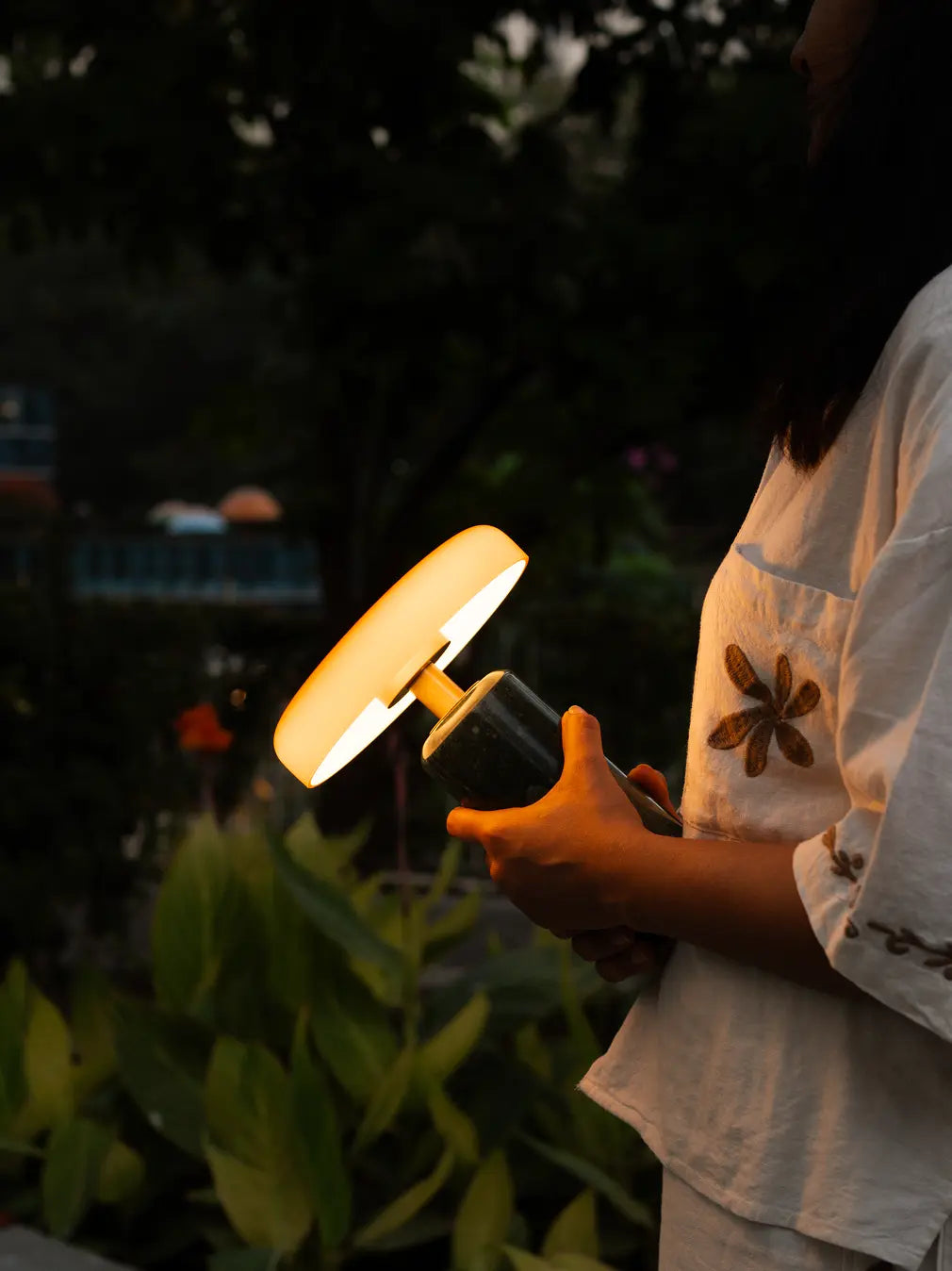 Person holding the Alba Moss Marble Table Lamp, highlighting its marble base and amber shade