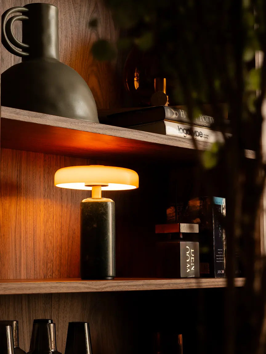 Alba Moss Marble Table Lamp glowing warmly on a wooden shelf for ambient home lighting