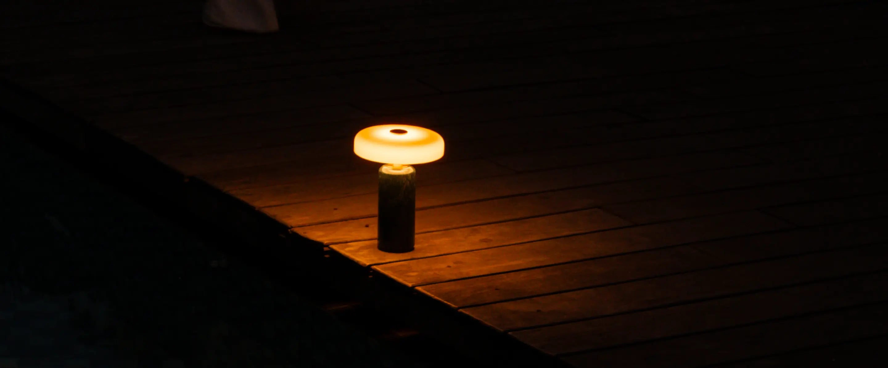 Alba Moss Marble Table Lamp glowing on a wooden deck for outdoor ambient lighting