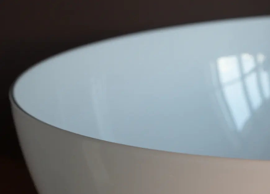 Close-up of glossy white glass dome shade of Arc Marble Table Lamp against dark background