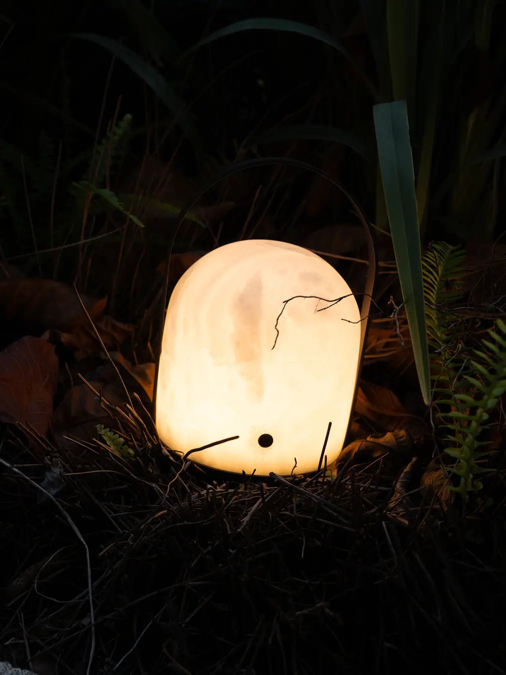 Portable marble table lamp casting a warm glow in an outdoor garden setting