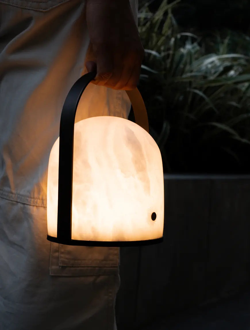 Arcus cordless marble table lamp carried by its black arched metal handle