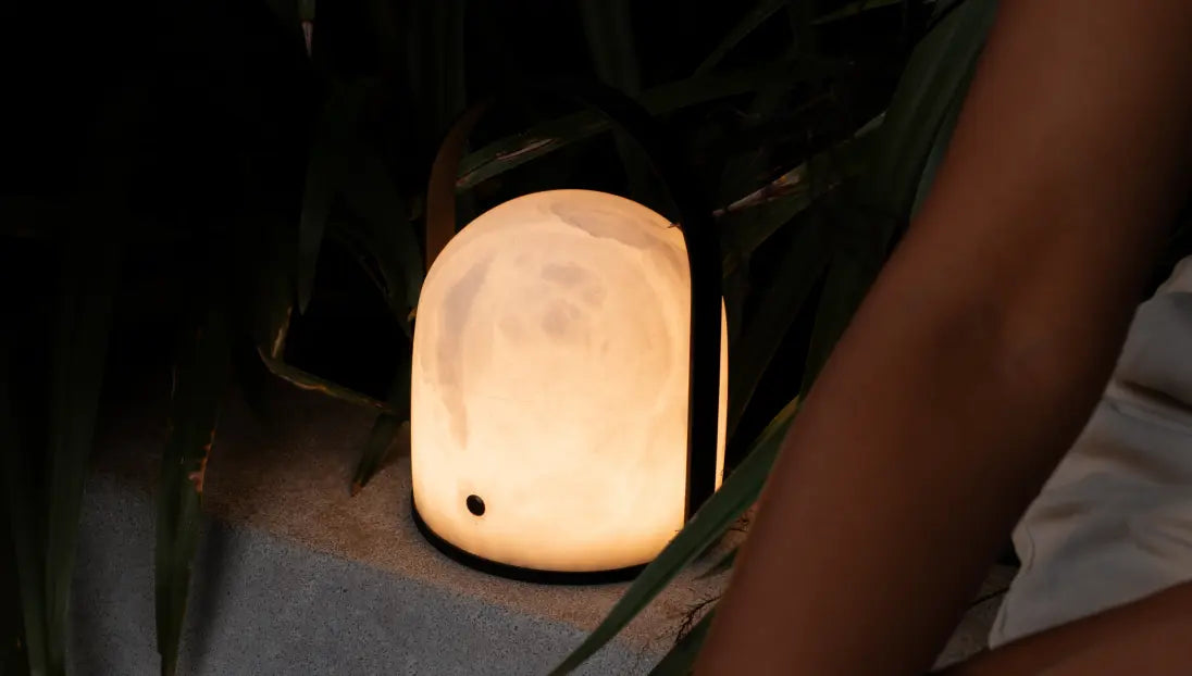 Arcus marble table lamp glowing warmly in a cosy outdoor garden setting