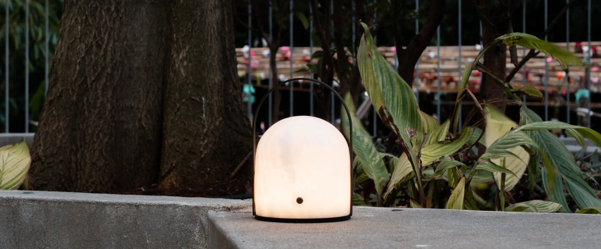 Arcus portable marble table lamp creating warm ambient light in an outdoor setting