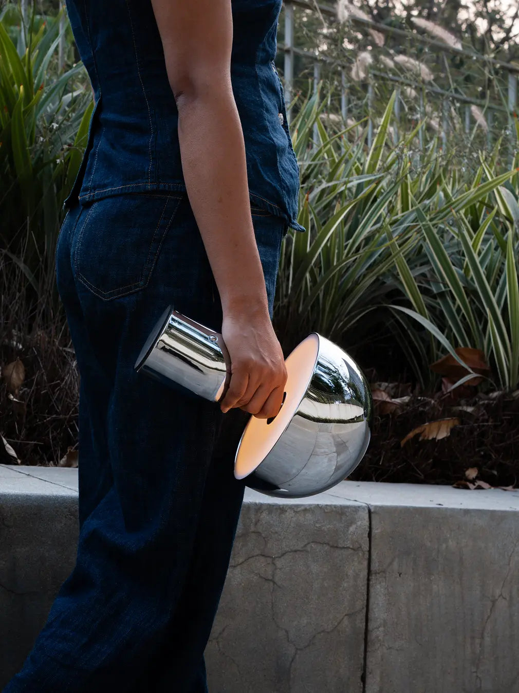 Chrome cordless table lamp carried outdoors with warm LED glow