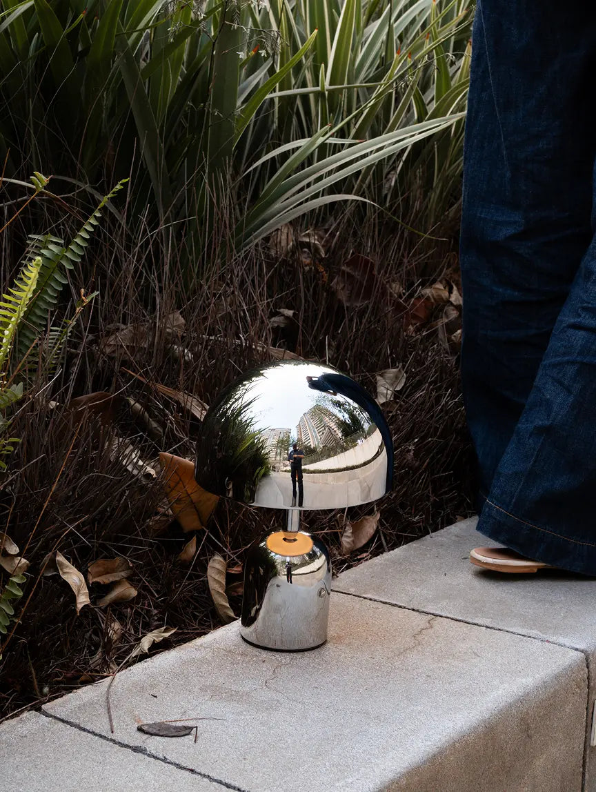 Bell Portable Table Lamp in chrome with warm LED glow outdoors