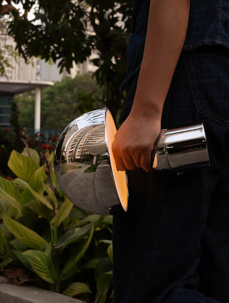 Cordless chrome table lamp carried outdoors with warm glow