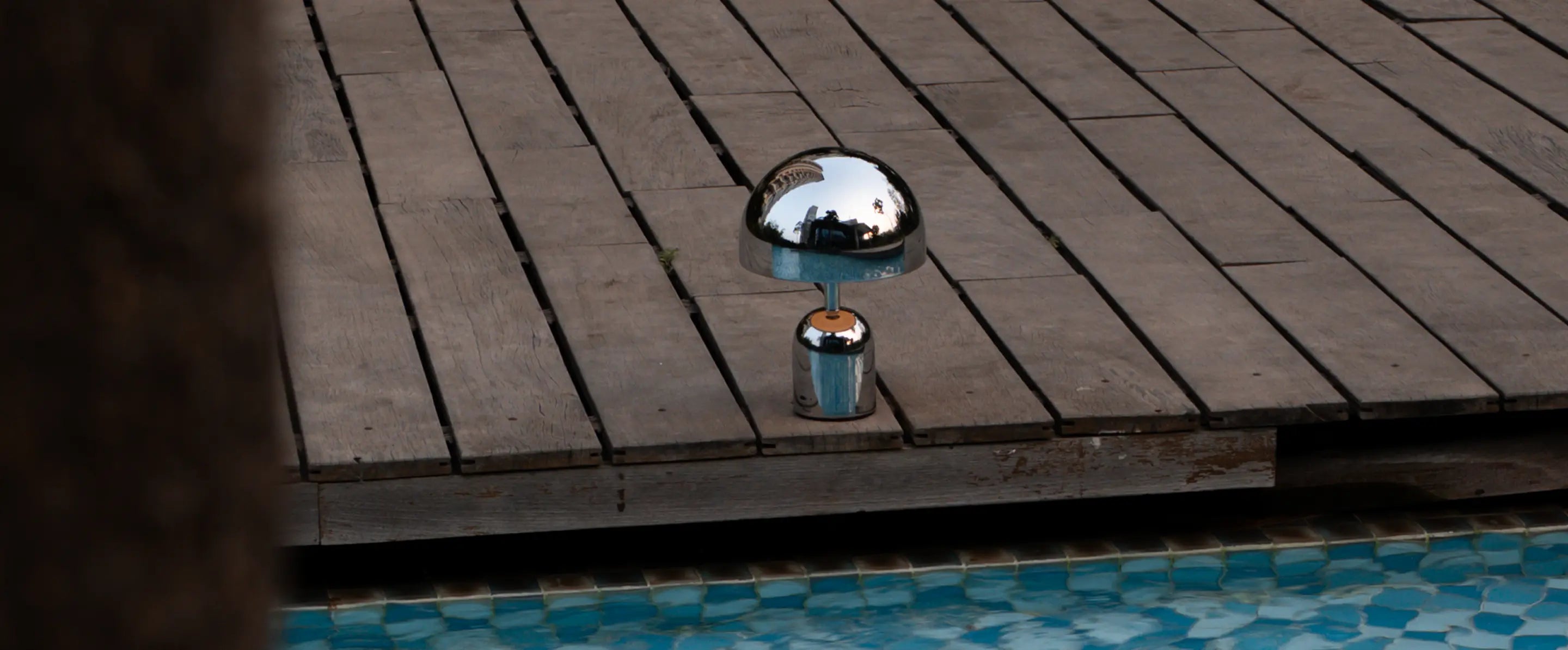 Bell chrome cordless table lamp placed near poolside deck