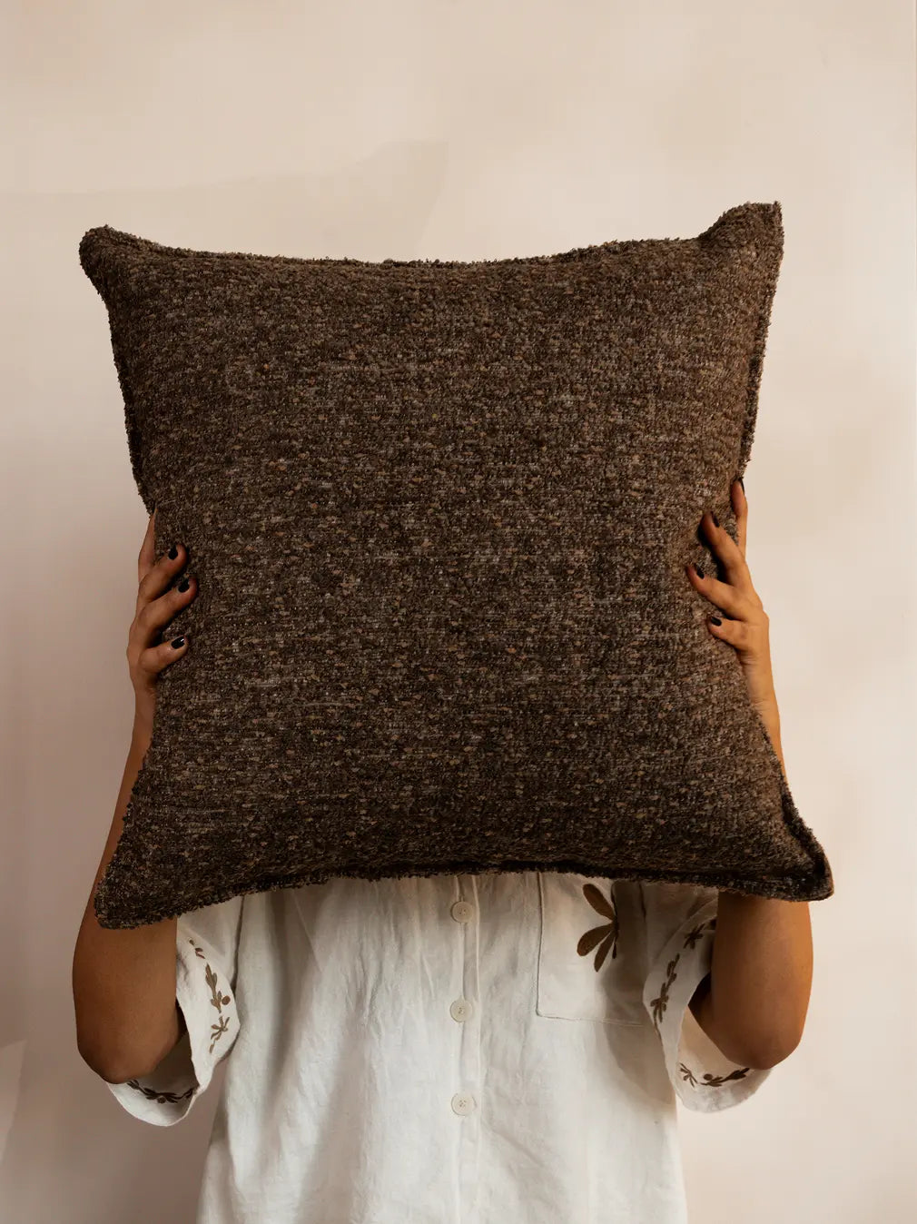 Boucle cushion cover with rich texture held against a neutral wall