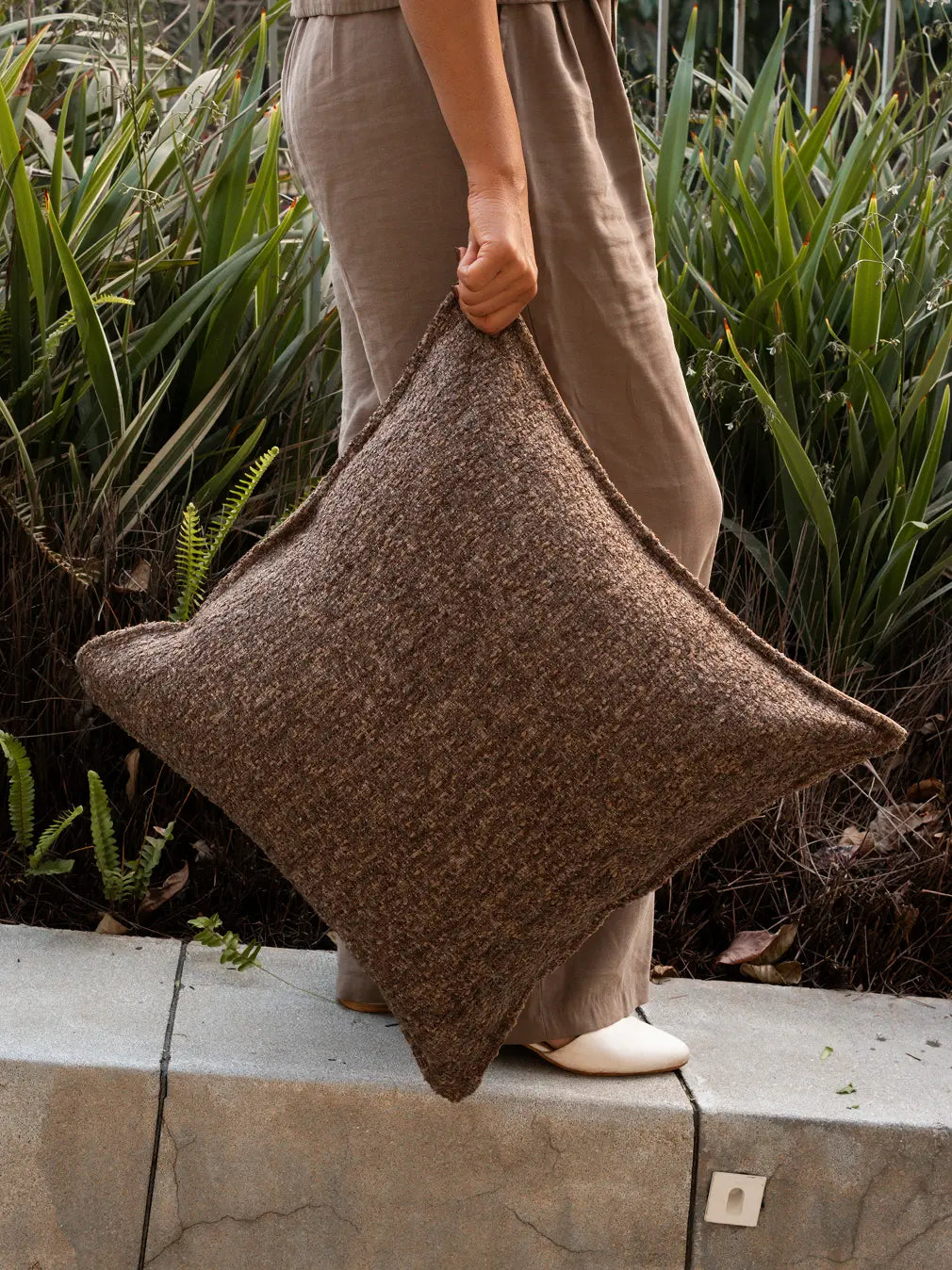 Brown boucle cushion cover with woven texture styled outdoors in natural light