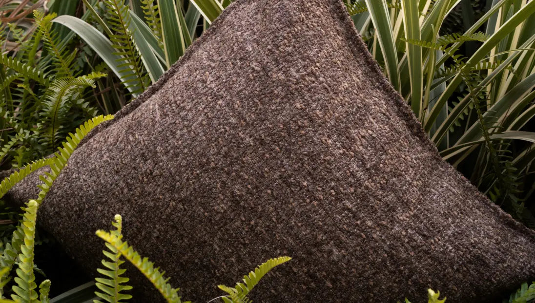Brown boucle cushion cover styled outdoors highlighting earthy modern home decor
