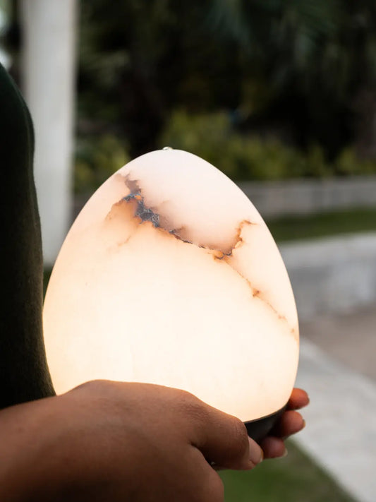 Bud Marble Portable Table Lamp held outdoors, showing warm glow and natural veining