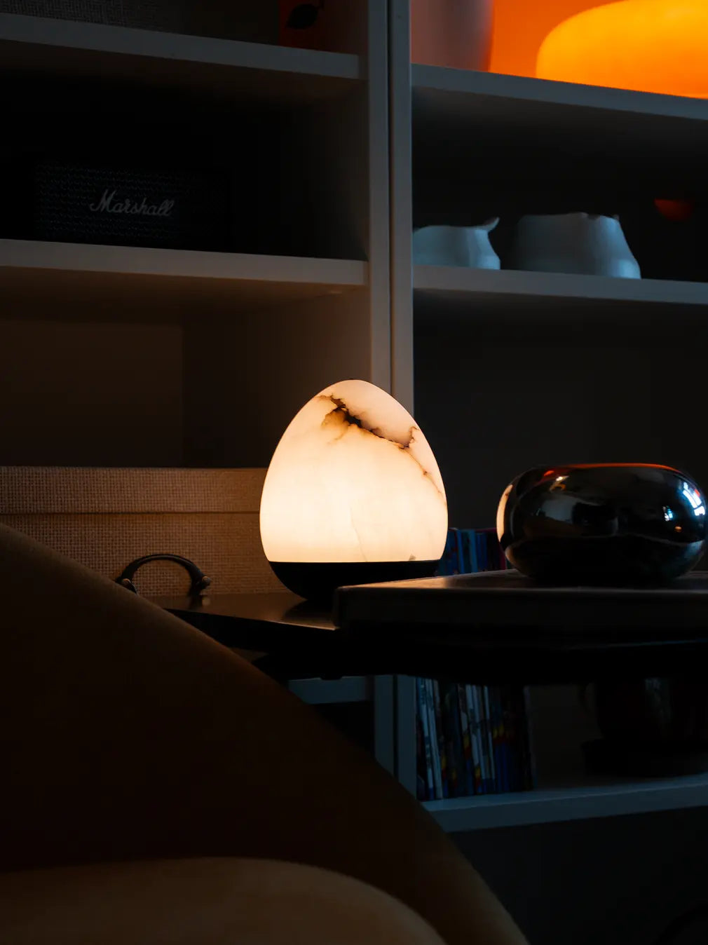 Bud Marble Portable Table Lamp glowing on a side table beside a sofa and bookshelf