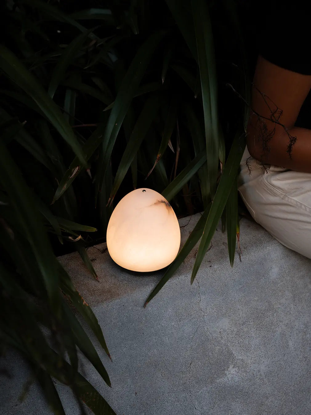 Glowing Bud Marble Portable Table Lamp styled beside green plants and outdoor seating