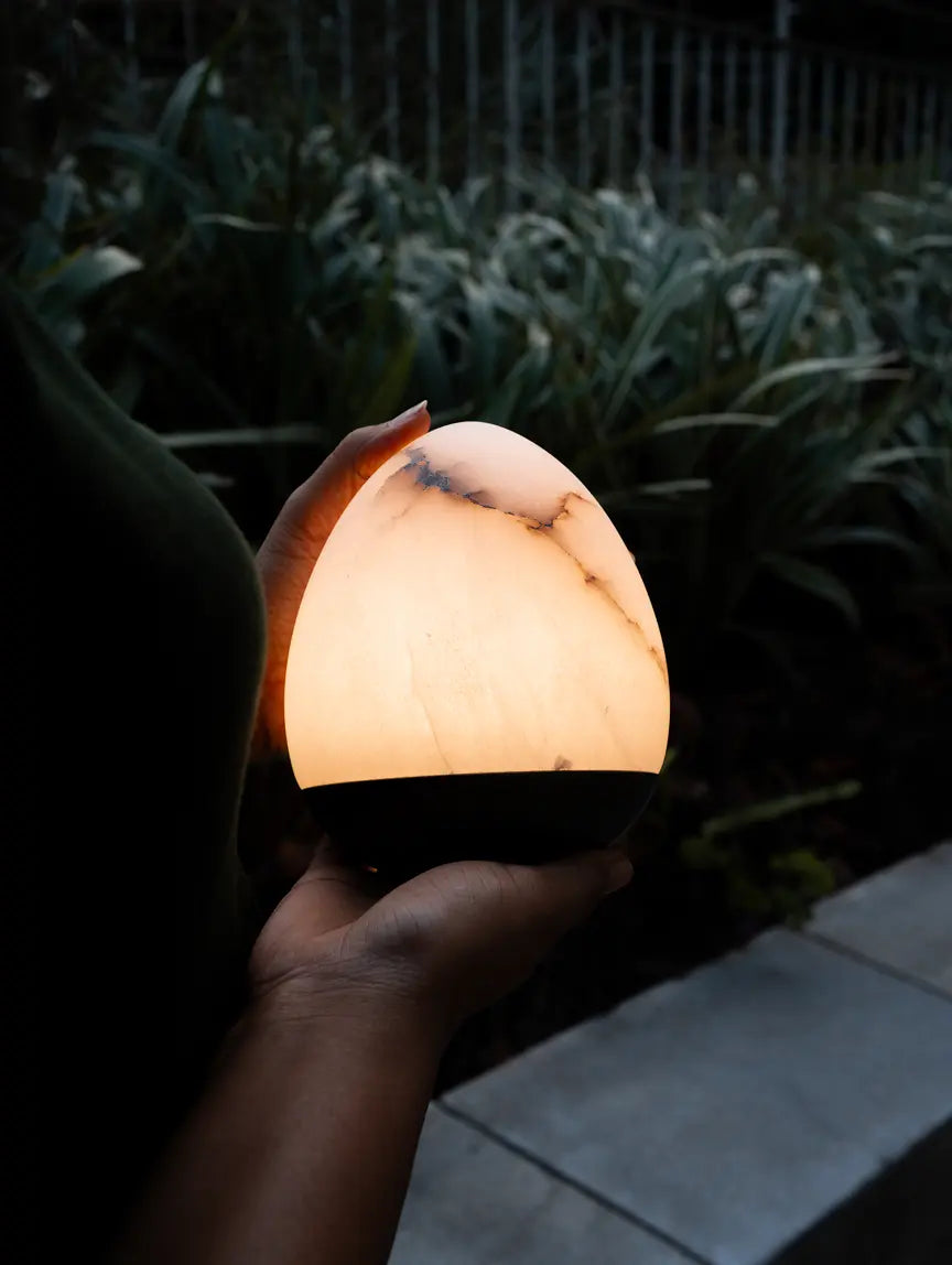 Bud Marble Portable Table Lamp held outdoors, showing warm glow and marble veining