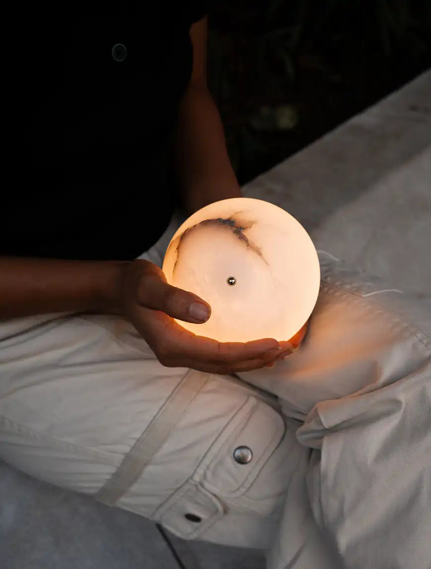 Glowing Bud Marble Portable Table Lamp cradled in hands to show its compact size