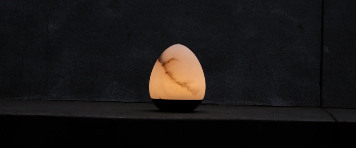 Bud Marble Portable Table Lamp casting a warm glow on a dark stone ledge