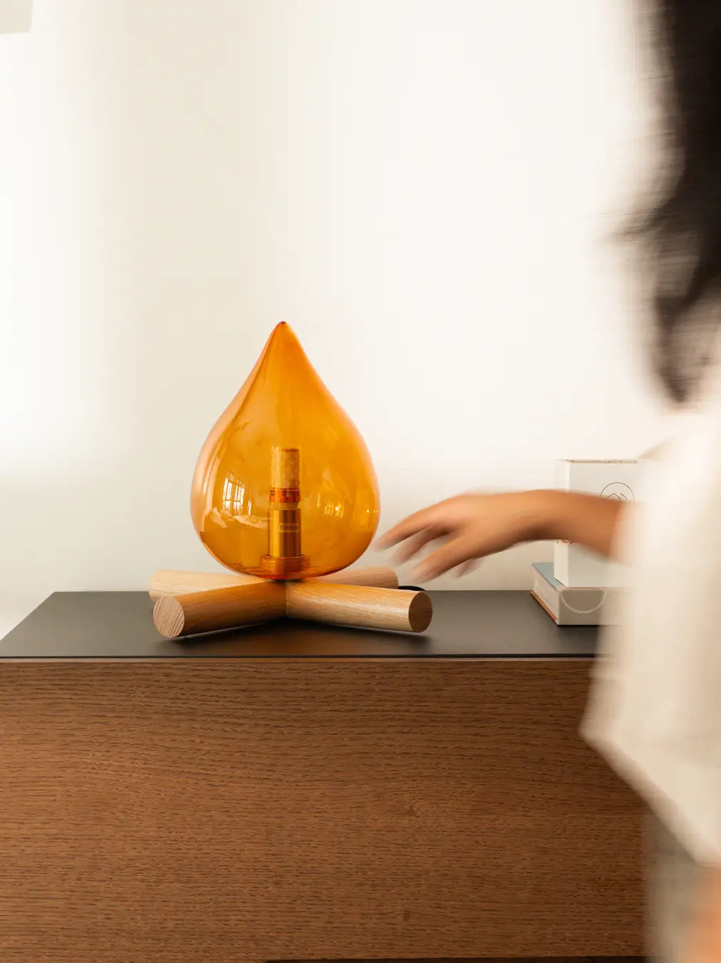 Orange lamp on a wooden surface with a blurred person in the foreground