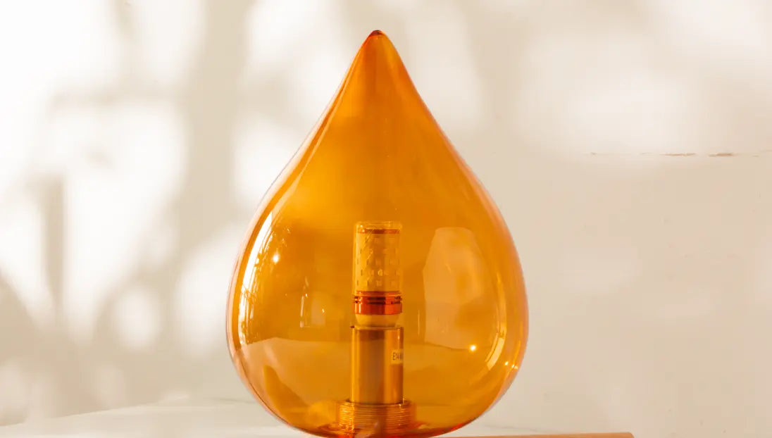 Orange teardrop-shaped lamp on white table in a light background