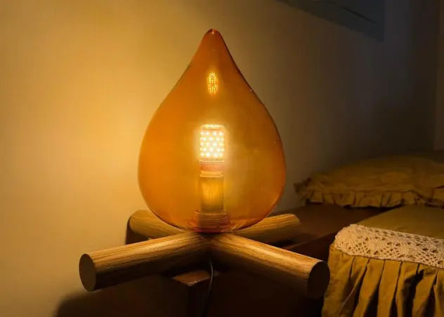 Decorative campfire lamp with a warm glow on a wooden base in a cozy room.