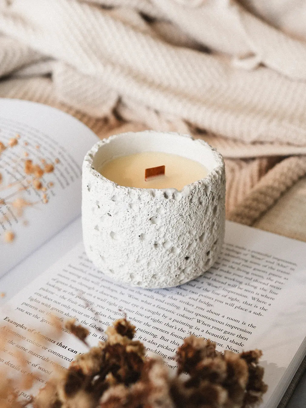 White Capri Concrete Candle on an open book with textured jar and clean soy wax surface