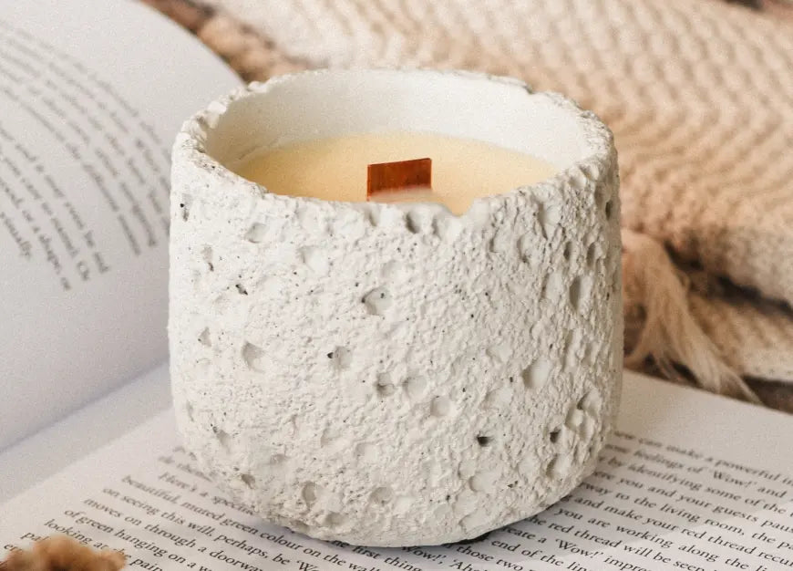 White Capri scented candle with wooden wick on an open book