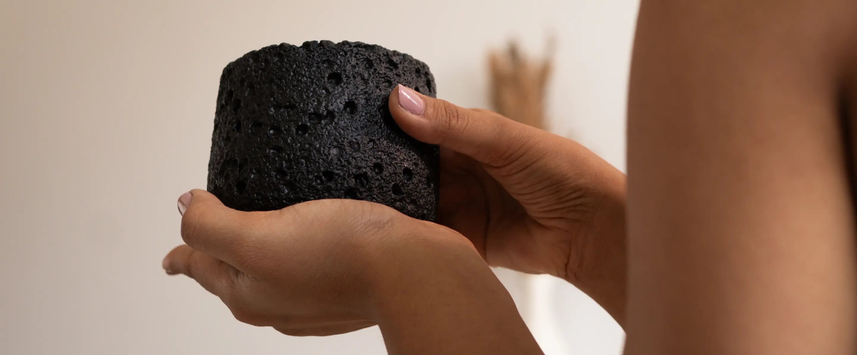 Side view of black Capri Candle highlighting raw textured concrete finish and rounded shape