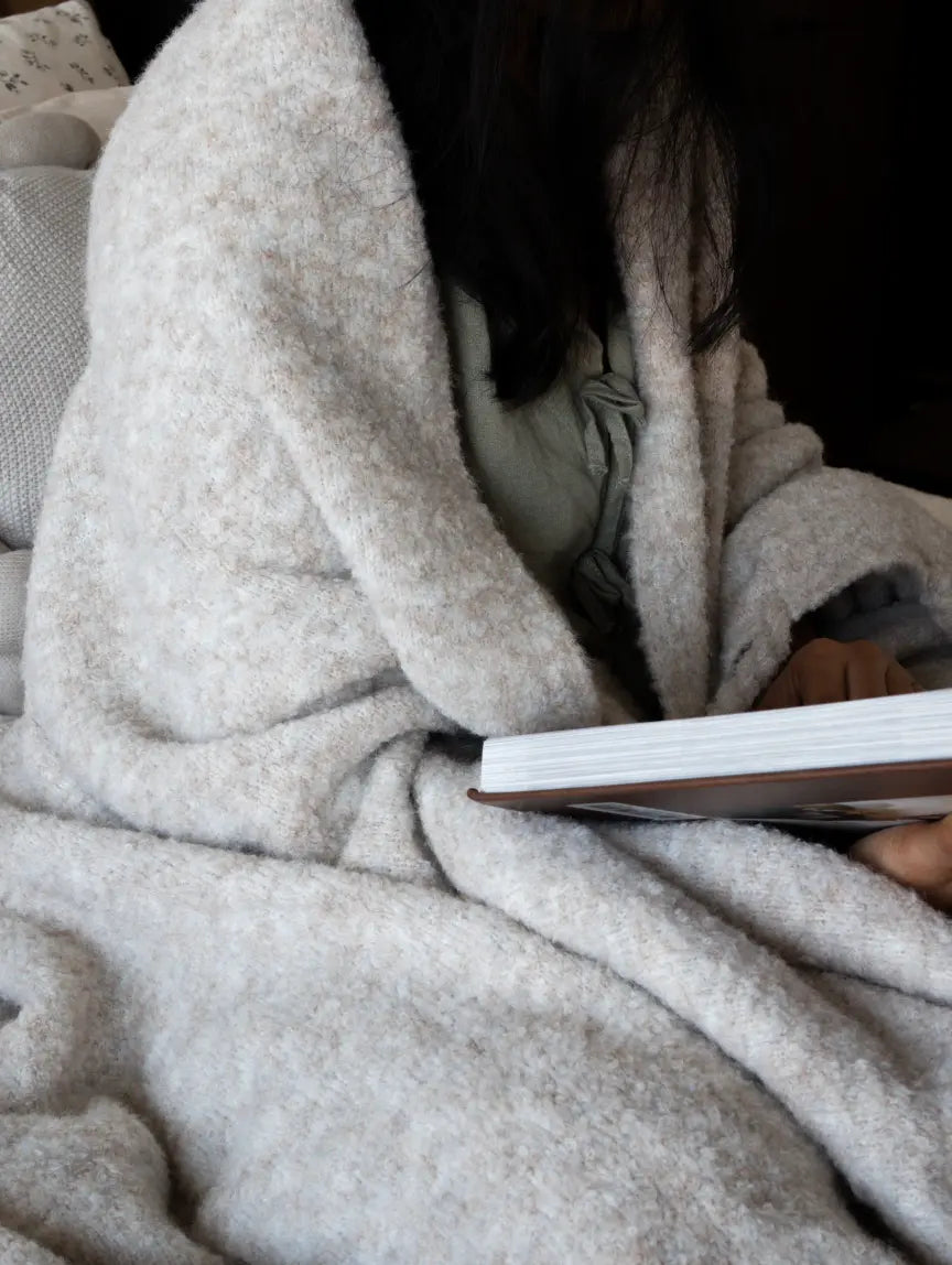 Person wrapped in cloud-soft wool throw blanket, perfect for cozy reading moments