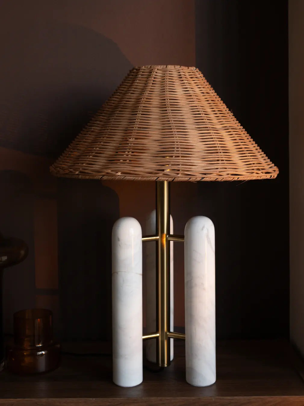 Table lamp with wicker shade and marble base on a dark background