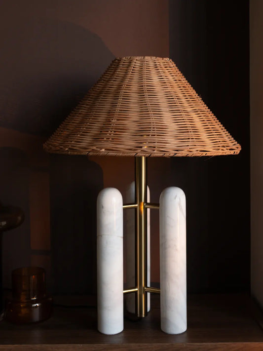 Table lamp with wicker shade and marble base on a dark background