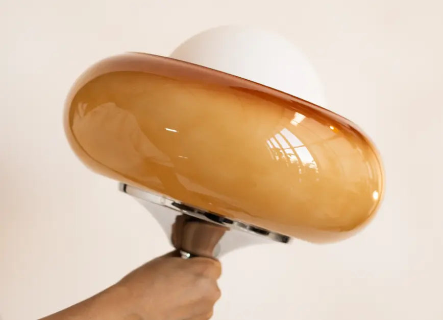 Hand holding the Dawn Glass Table Lamp showcasing its premium glass shade and polished silver base in natural light.