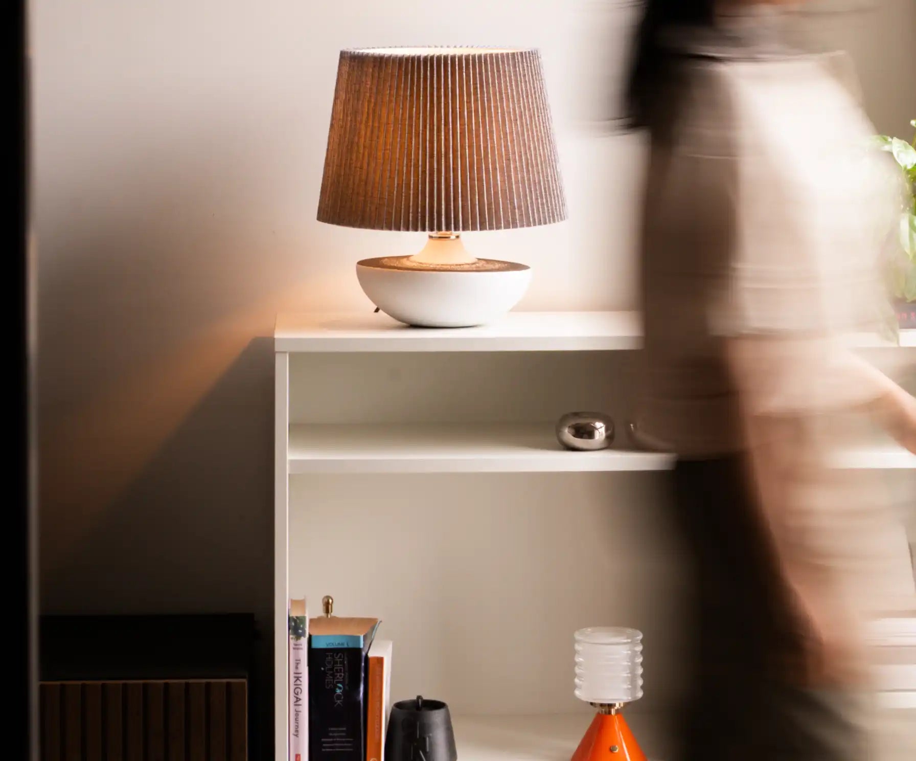 Lamp on a shelf with a blurred person in the foreground