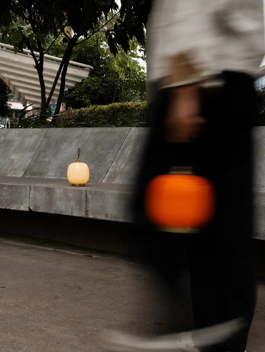 Dew portable glass table lamps glowing outdoors in orange and warm white