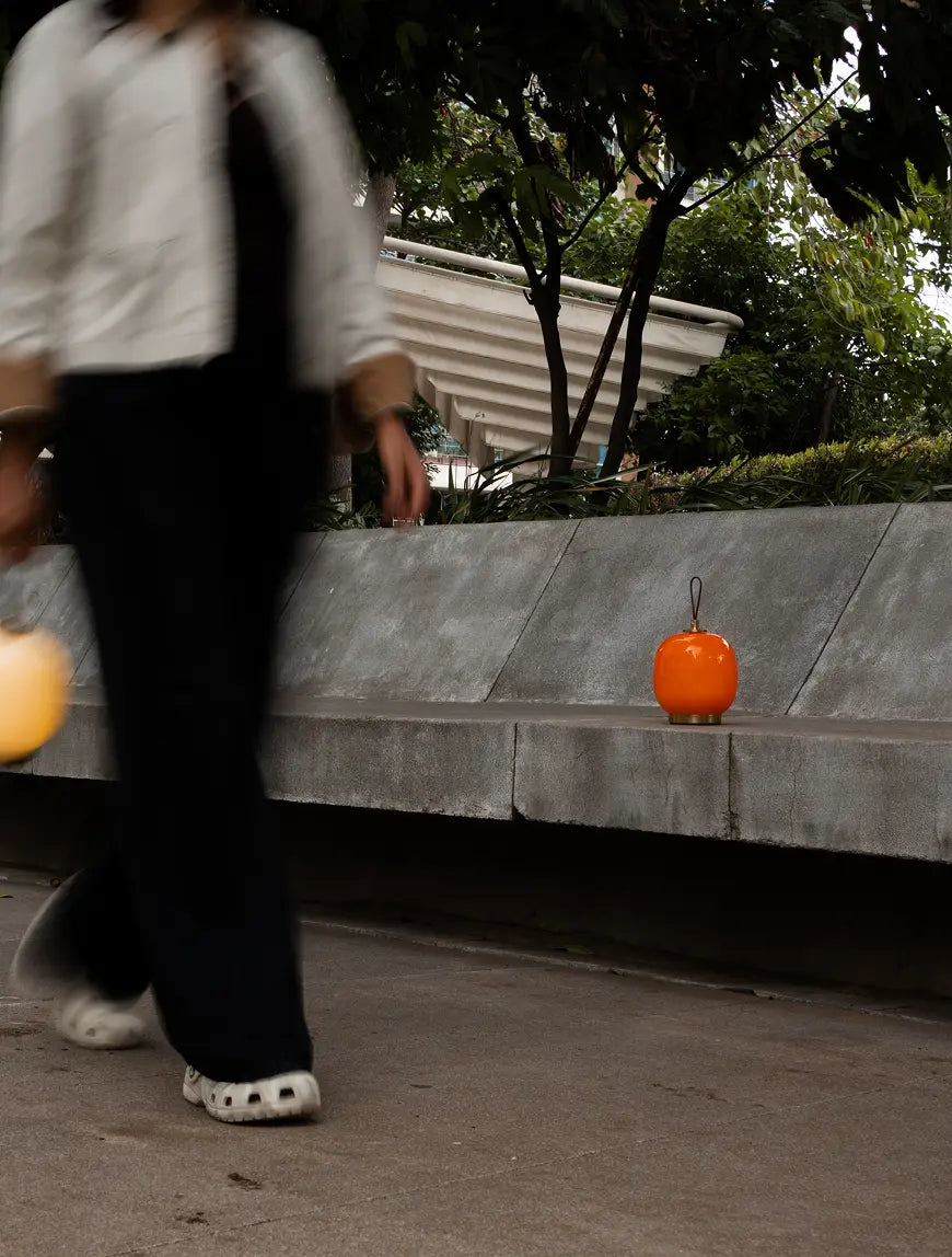 Orange Dew cordless table lamp styled outdoors on a concrete bench