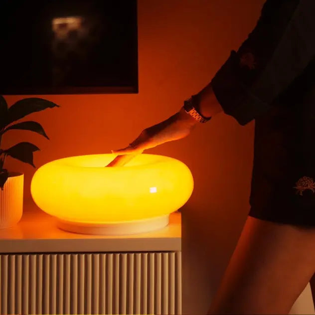 Customer interacting with a donut light on a table in a warm-toned room.