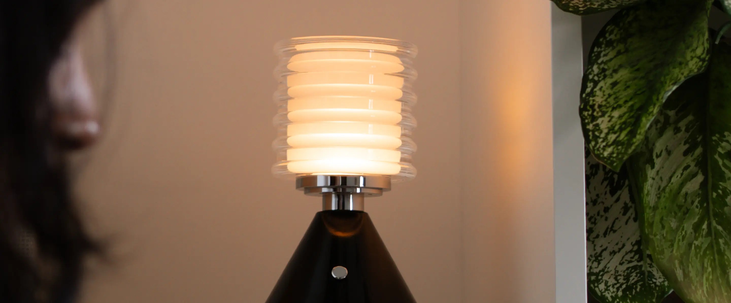Decorative Table Lamp with ribbed glass shade, black base, and warm LED lamp, styled in a cozy setting