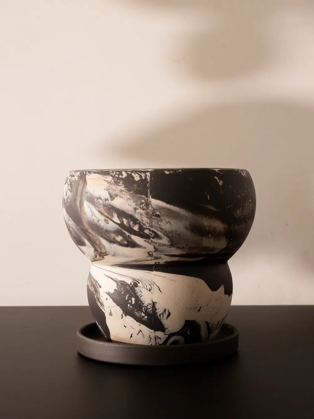 Black and white ceramic pot on a dark surface with a neutral background