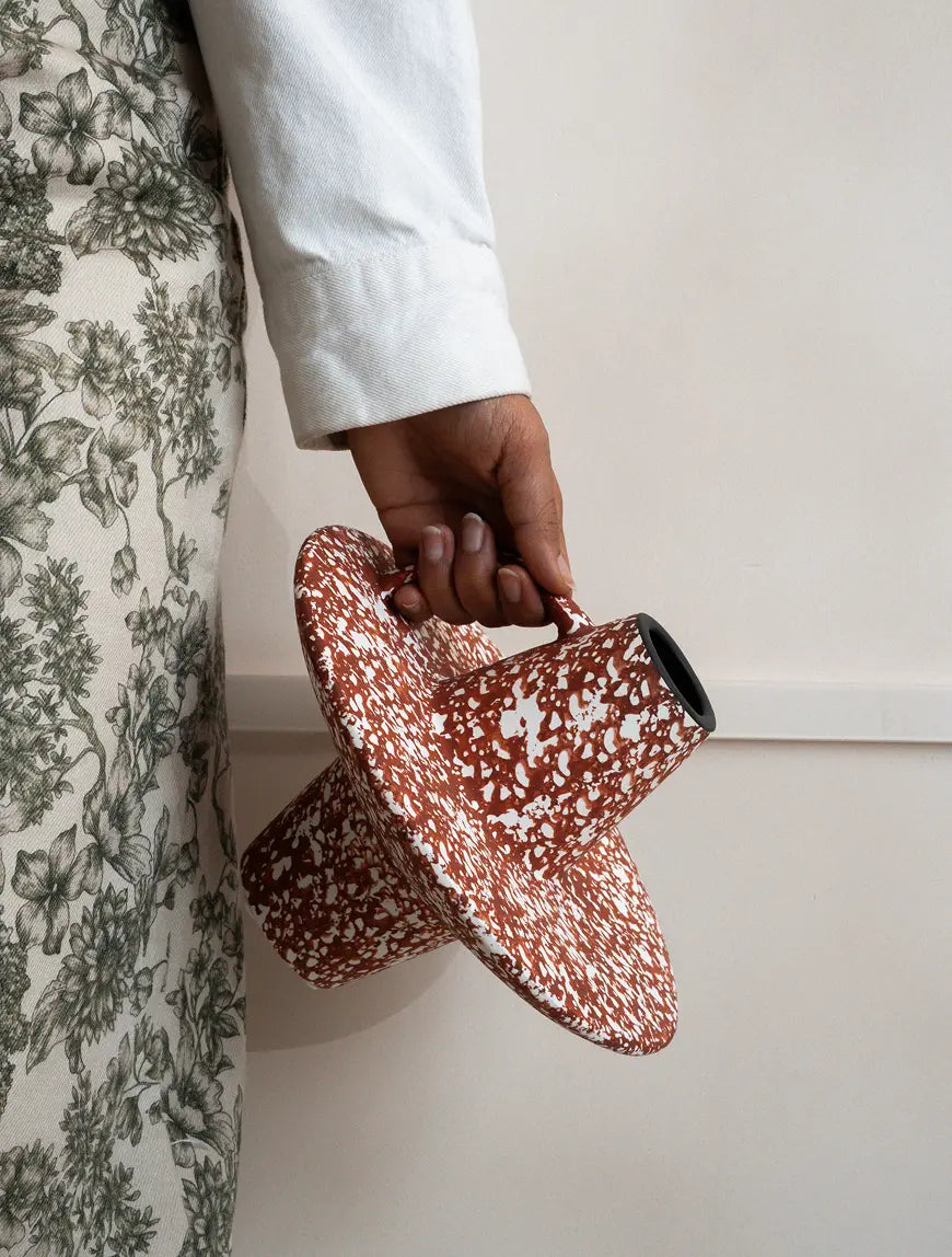 Handheld sculptural ceramic vase highlighting wide disc base design