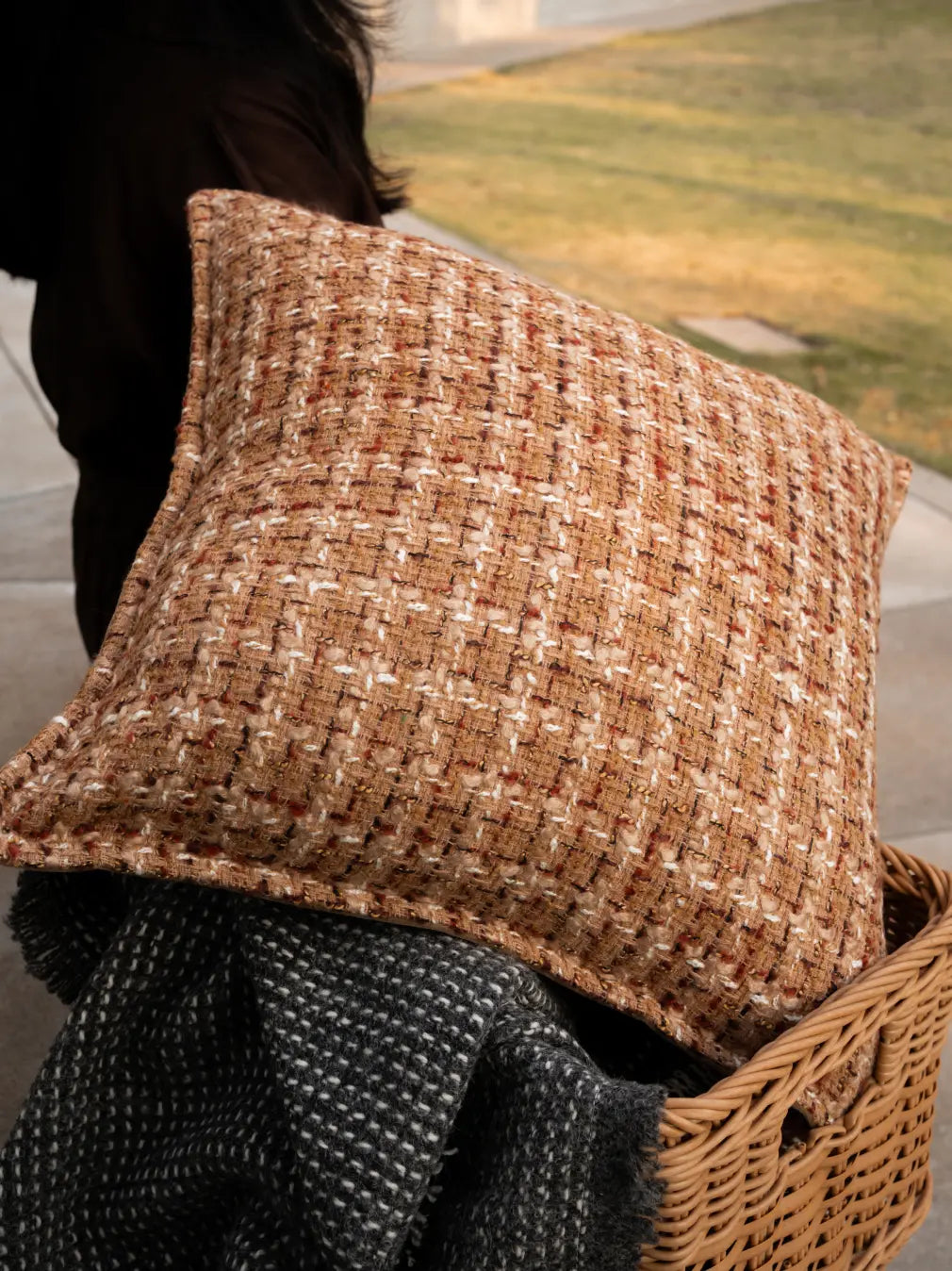 Textured Fleck cushion cover styled on storage basket, adding warmth and depth to decor.