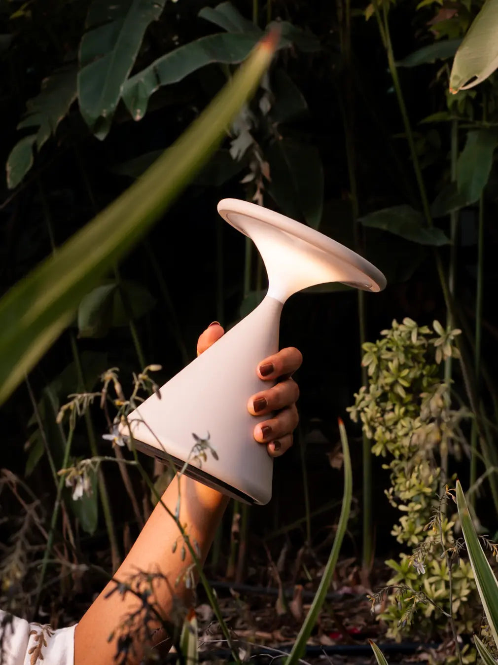 Bone Flux Portable Table Lamp held in hand in a natural outdoor environment