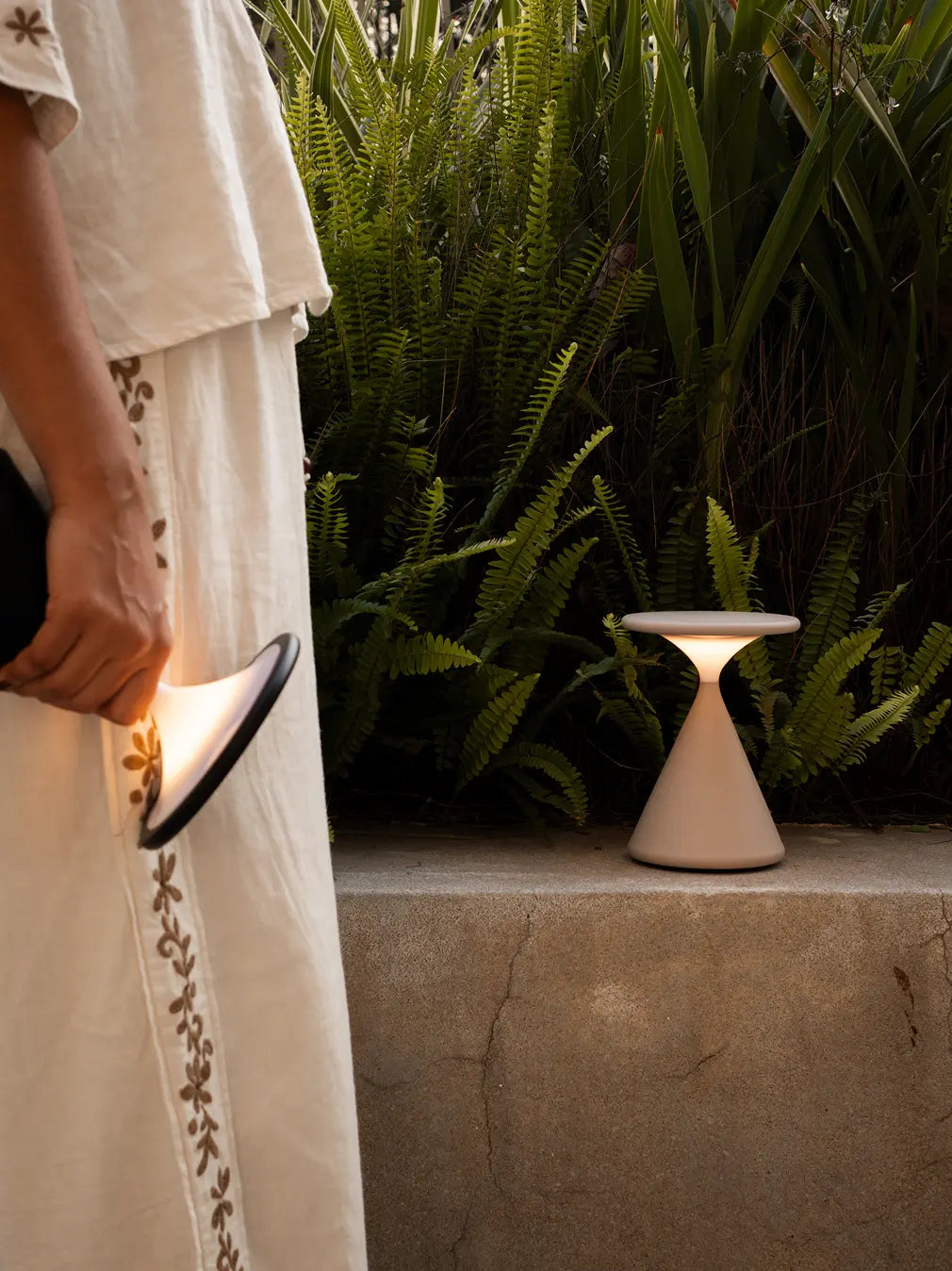Flux Portable Table Lamp placed outdoors on stone ledge creating warm ambient light