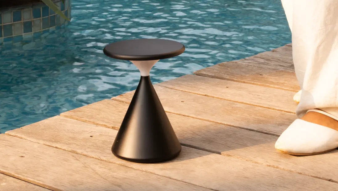 Black Flux Portable Table Lamp kept by the poolside showcasing modern cordless style.