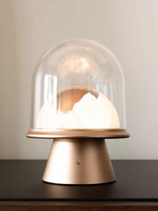 Decorative cordless lamp with glass dome and wooden base on a neutral background