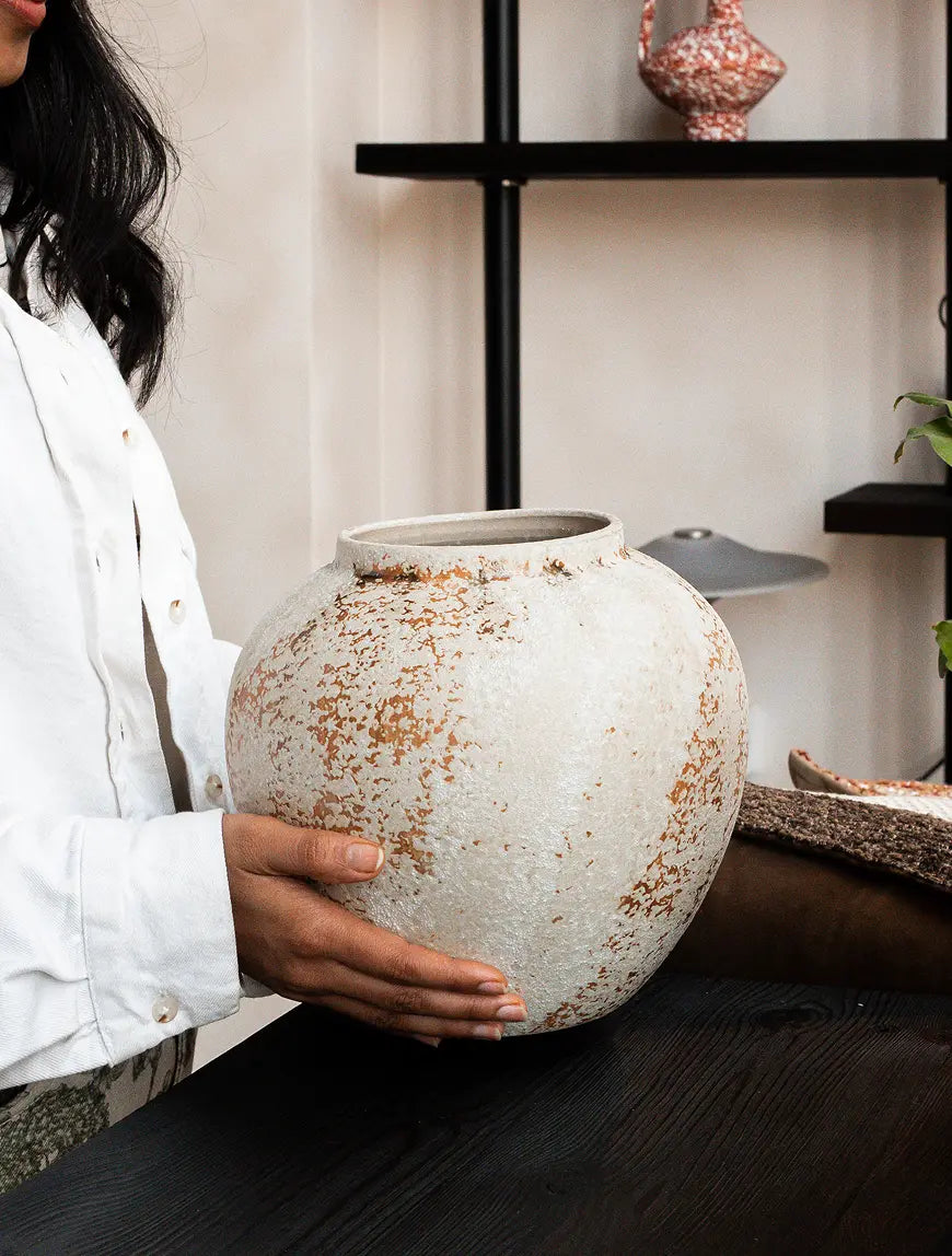 Handmade Gaia ceramic vase held by hand highlighting rounded sculptural form