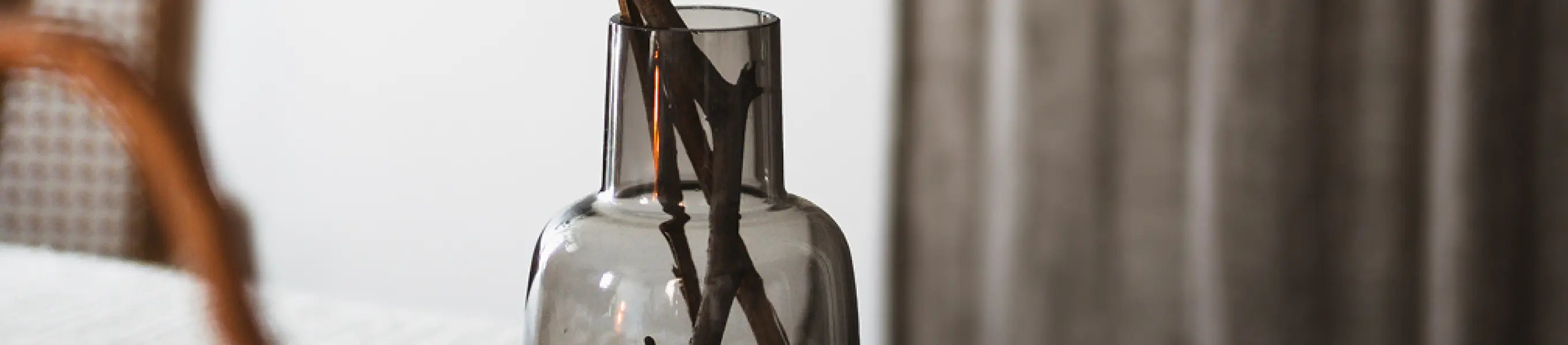 Glass vase with dried branches placed on a table in a modern home setting.